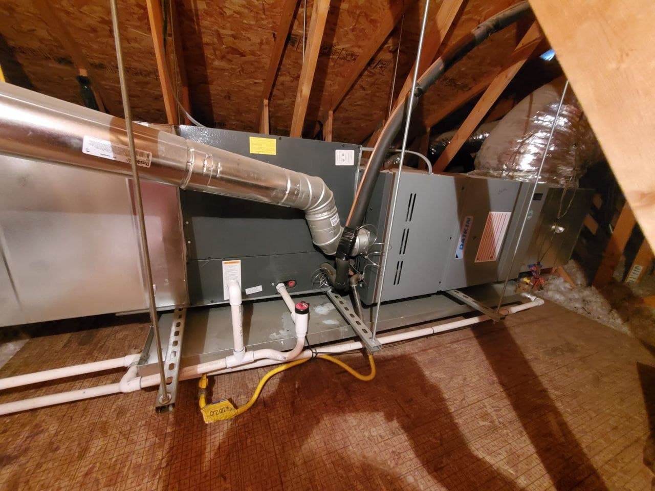 A newly installed Daikin furnace and coil in an attic, with flue, gas line and condensate drain run to it