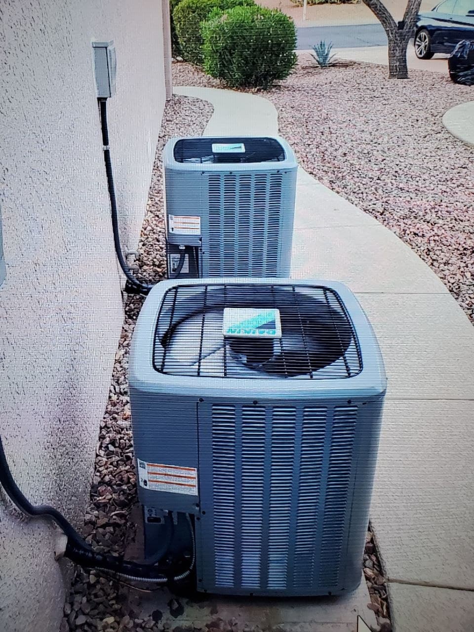 Two Daikin heat pump condensers installed side by side along the wall of a Phoenix home